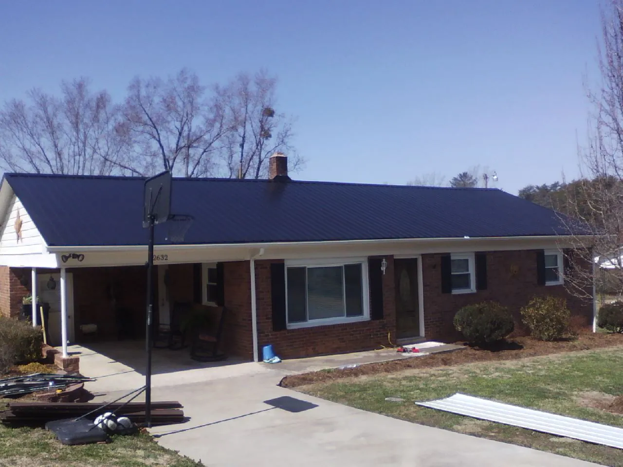 Finished dark blue metal roof on a brick ranch with a carport in Ashford