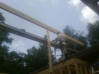 Carpenter setting a ridge beam over a new addition frame — Ice Dam Removal by Roofing Brothers in Ashford